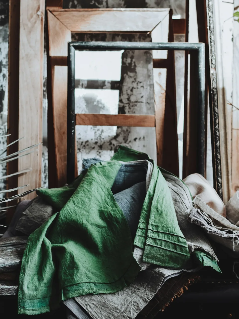 Tela de lino verde extendida sobre armazones de madera desnudos en un taller de tapicería